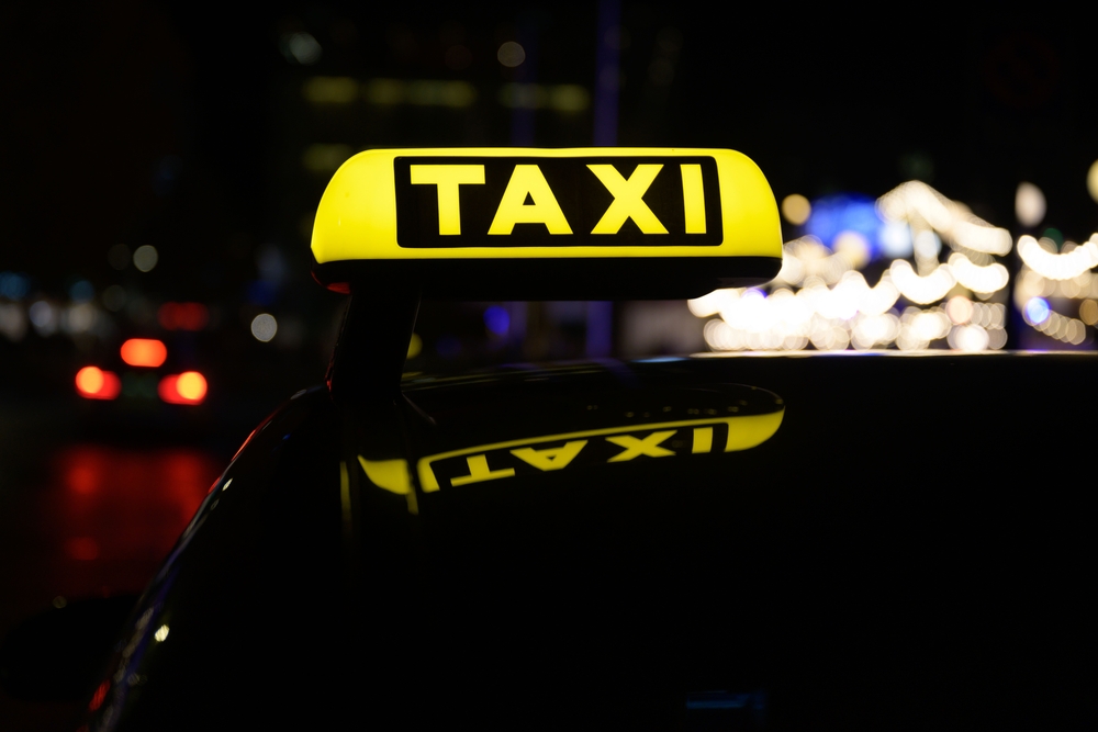 A,Yellow,Taxi,Sign,Illuminated,By,The,Daylight,,Mounted,On